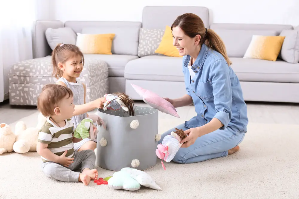 Image of mom helping with chores for kids, putting toys away with two children