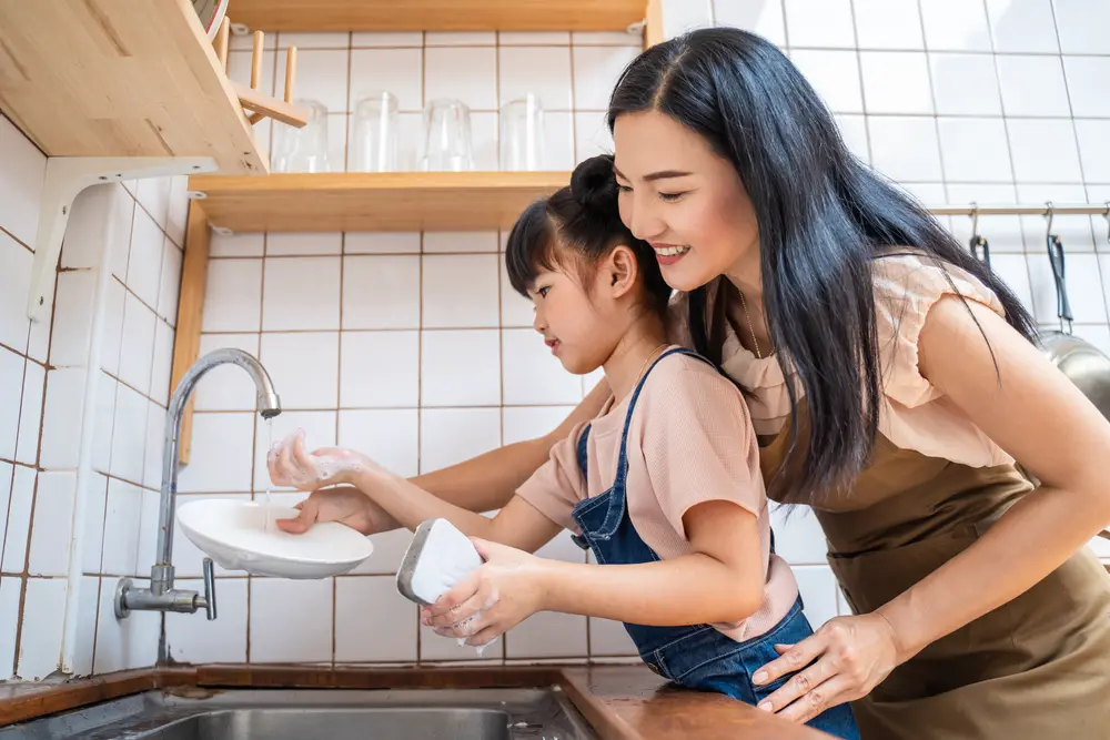 Image of mother and child washing dishes in a stay at home mom schedule